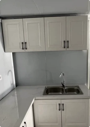 A modern, clean kitchen in an expandable home features stone benchtops and sleek cupboards.